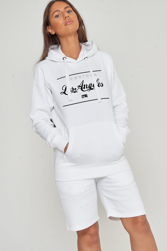 Woman wearing the white Los Angeles Oversized Hoodie styled with casual bottoms, highlighting the bold front graphic and comfortable oversized fit.