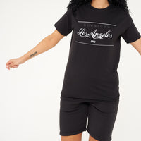 Woman wearing the black Los Angeles Oversized T-Shirt styled with casual bottoms, highlighting the bold front graphic and comfortable oversized fit.