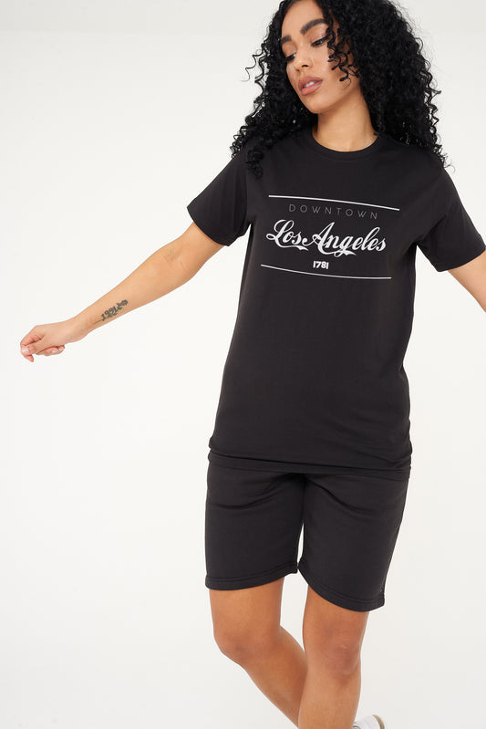 Woman wearing the black Los Angeles Oversized T-Shirt styled with casual bottoms, highlighting the bold front graphic and comfortable oversized fit.