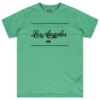 Green oversized women’s T-shirt featuring a bold white “Los Angeles” graphic printed prominently on the chest, classic round neckline, and short sleeves.