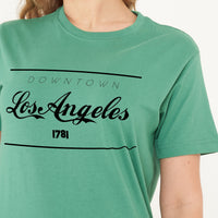 Woman wearing the green Los Angeles Oversized T-Shirt styled with casual bottoms, highlighting the bold front print and comfortable oversized fit.