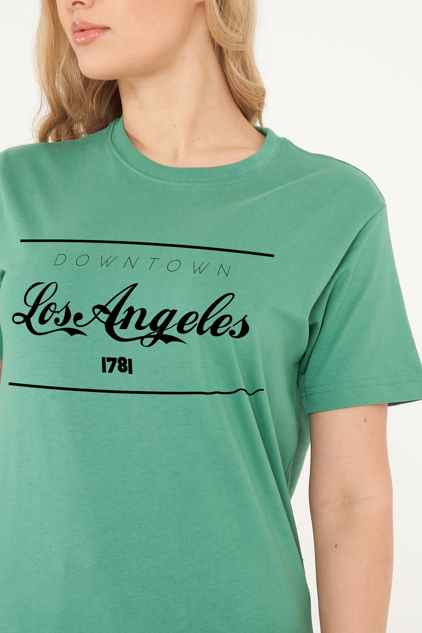 Woman wearing the green Los Angeles Oversized T-Shirt styled with casual bottoms, highlighting the bold front print and comfortable oversized fit.