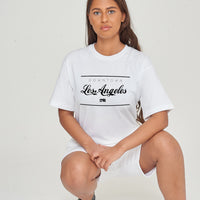 Woman wearing the white Los Angeles Oversized T-Shirt styled with casual bottoms, showcasing the bold front graphic and comfortable oversized fit.