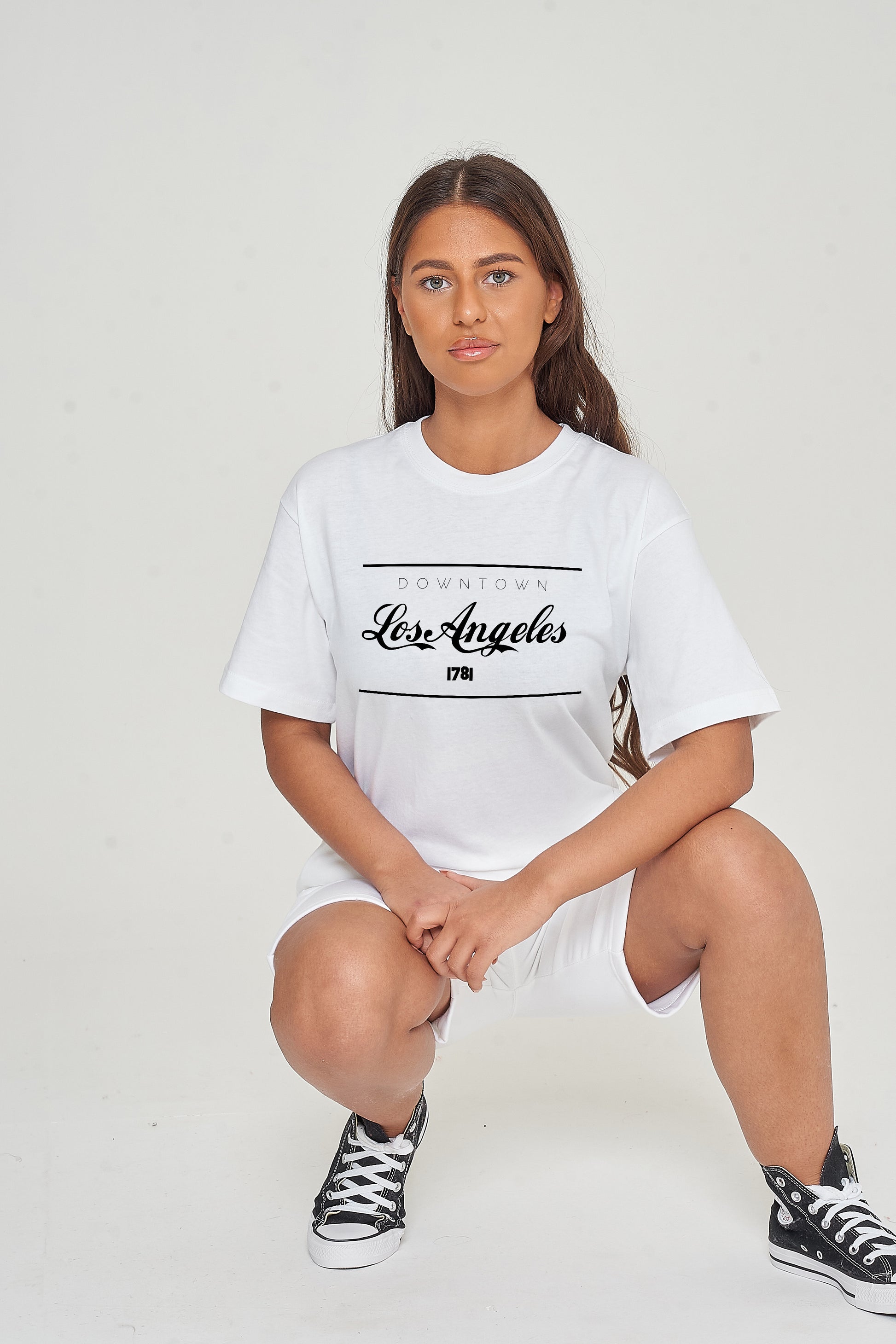 Woman wearing the white Los Angeles Oversized T-Shirt styled with casual bottoms, showcasing the bold front graphic and comfortable oversized fit.