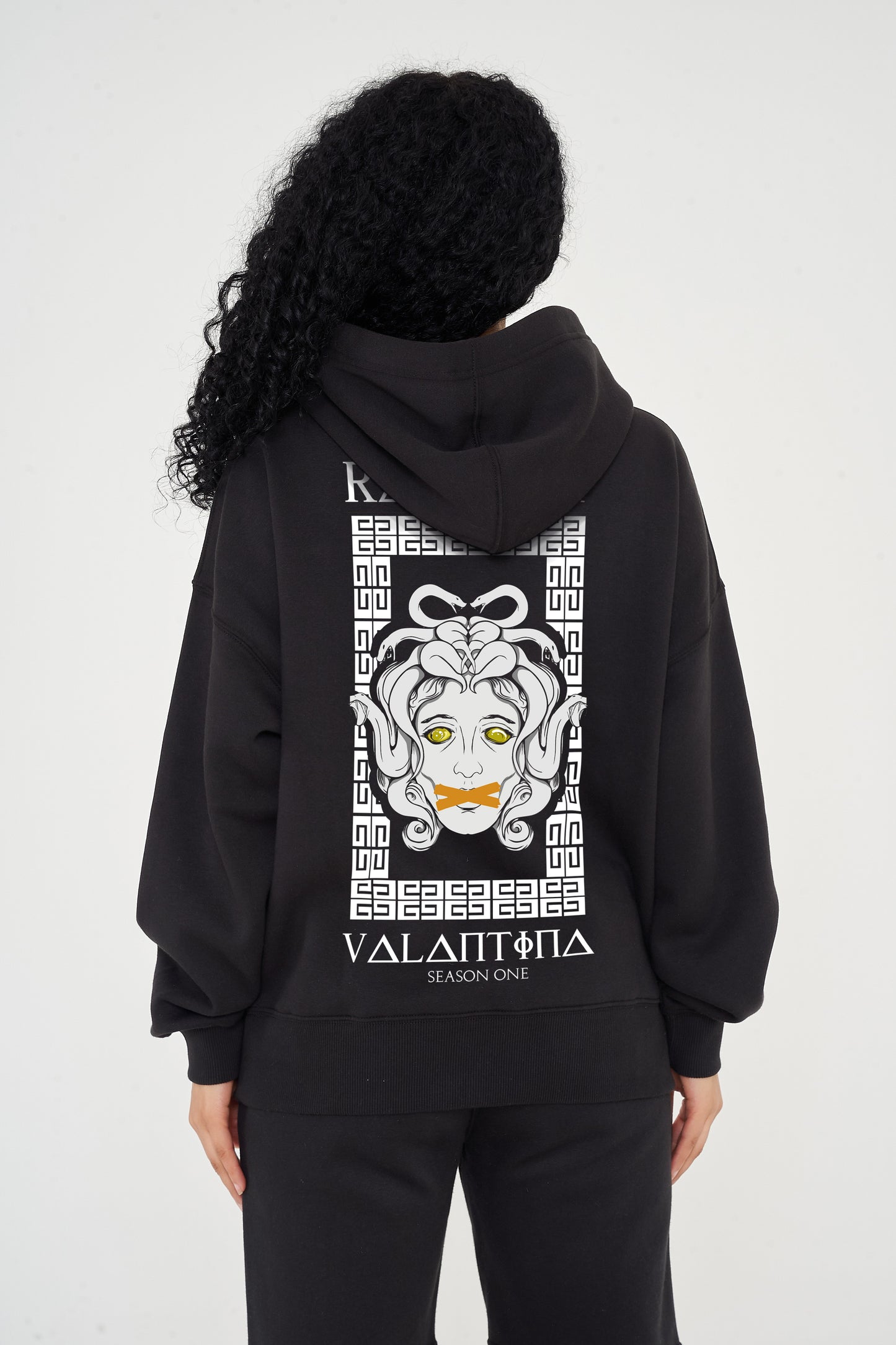 Woman wearing the Medusa Oversized Hoodie (black), styled with casual bottoms, highlighting the large back graphic and comfortable silhouette.
