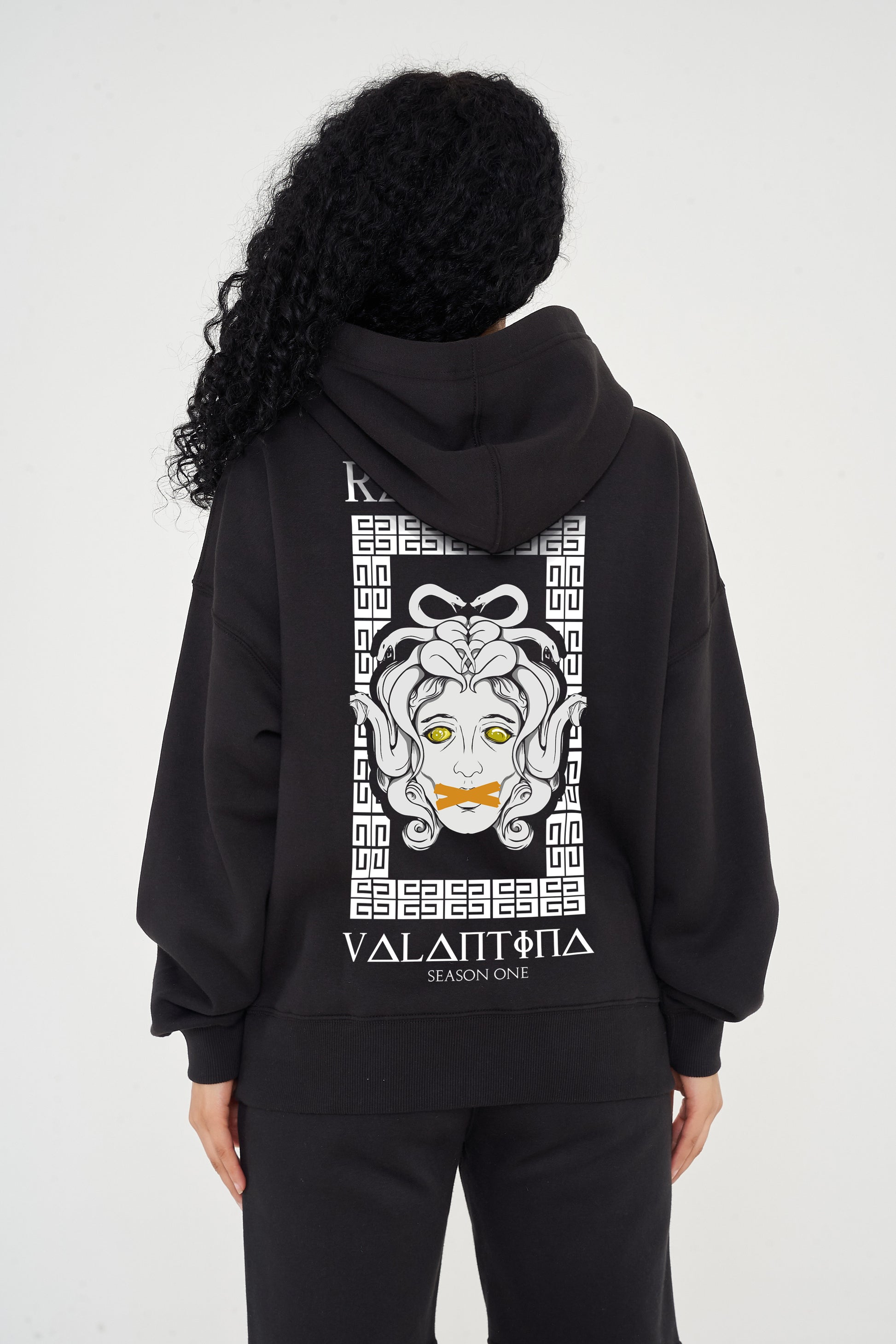 Woman wearing the Medusa Oversized Hoodie (black), styled with casual bottoms, highlighting the large back graphic and comfortable silhouette.