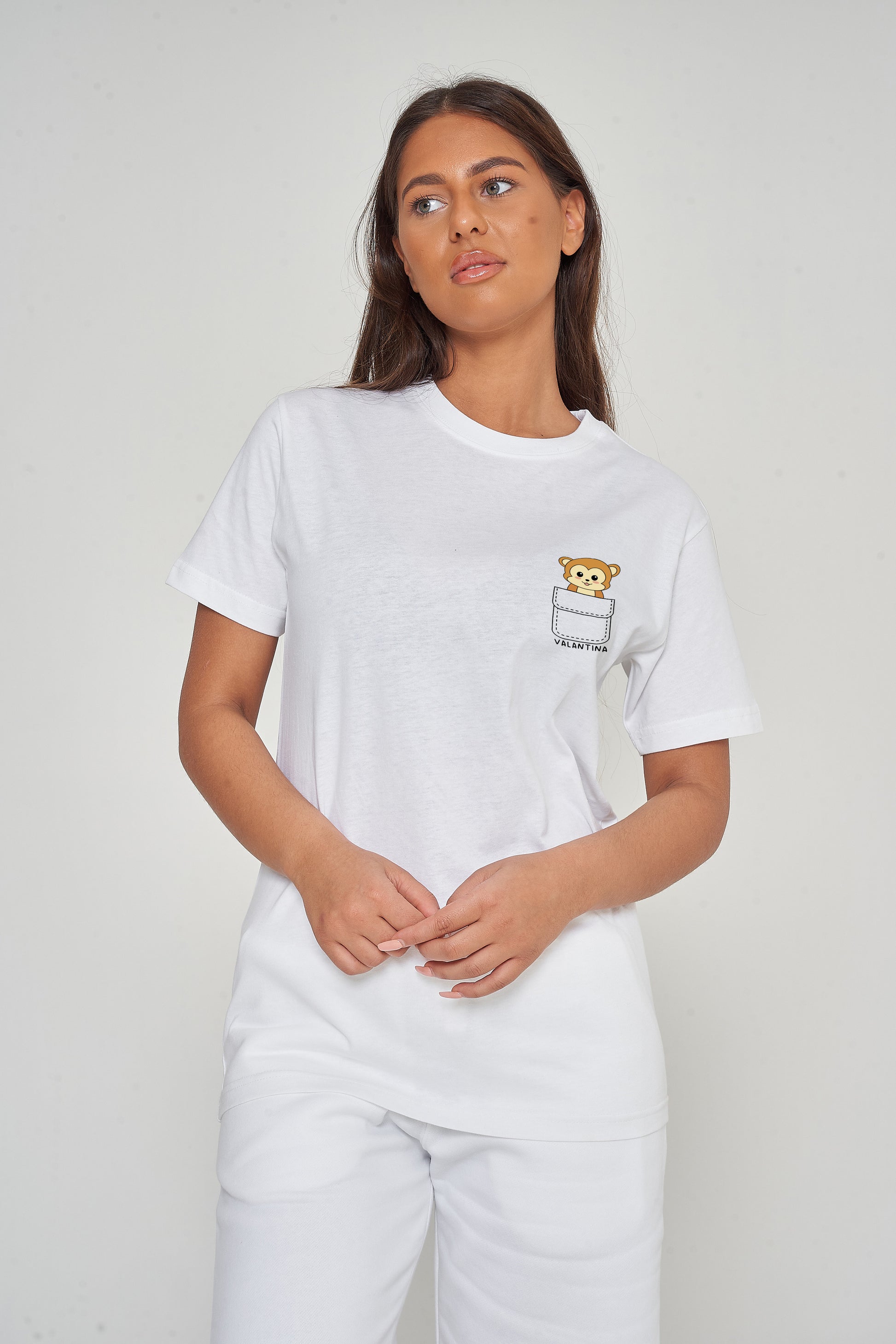 Woman wearing the white Monkey Pocket T-Shirt styled with casual bottoms, highlighting the playful front monkey graphic and comfortable oversized fit. 