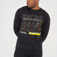 Man wearing the black New York Season 1 Sweatshirt styled with casual bottoms, showcasing the front graphic and comfortable fit.