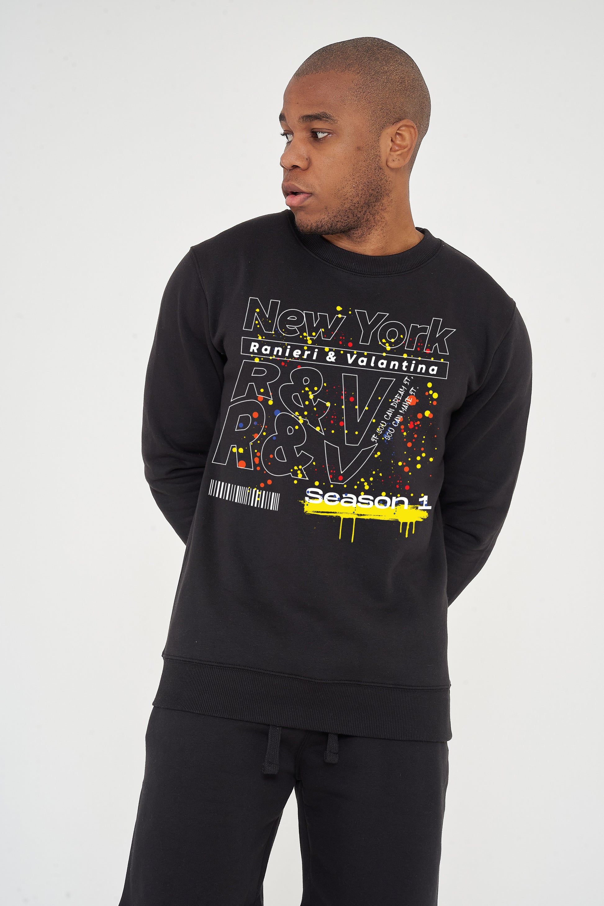 Man wearing the black New York Season 1 Sweatshirt styled with casual bottoms, showcasing the front graphic and comfortable fit.