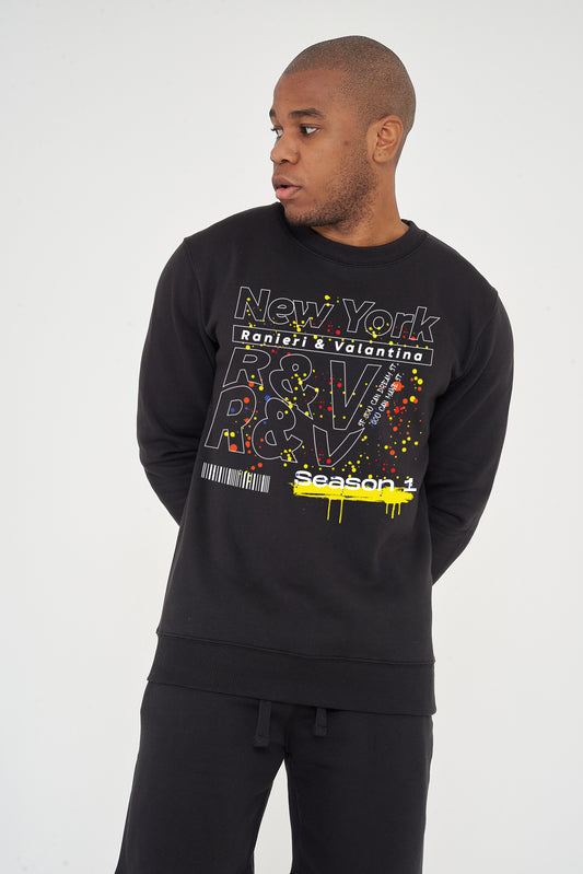 Man wearing the black New York Season 1 Sweatshirt styled with casual bottoms, showcasing the front graphic and comfortable fit.