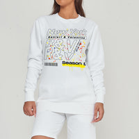 Woman wearing the white New York Season 1 Sweatshirt styled with casual bottoms, highlighting the prominent front graphic print and comfortable fit.