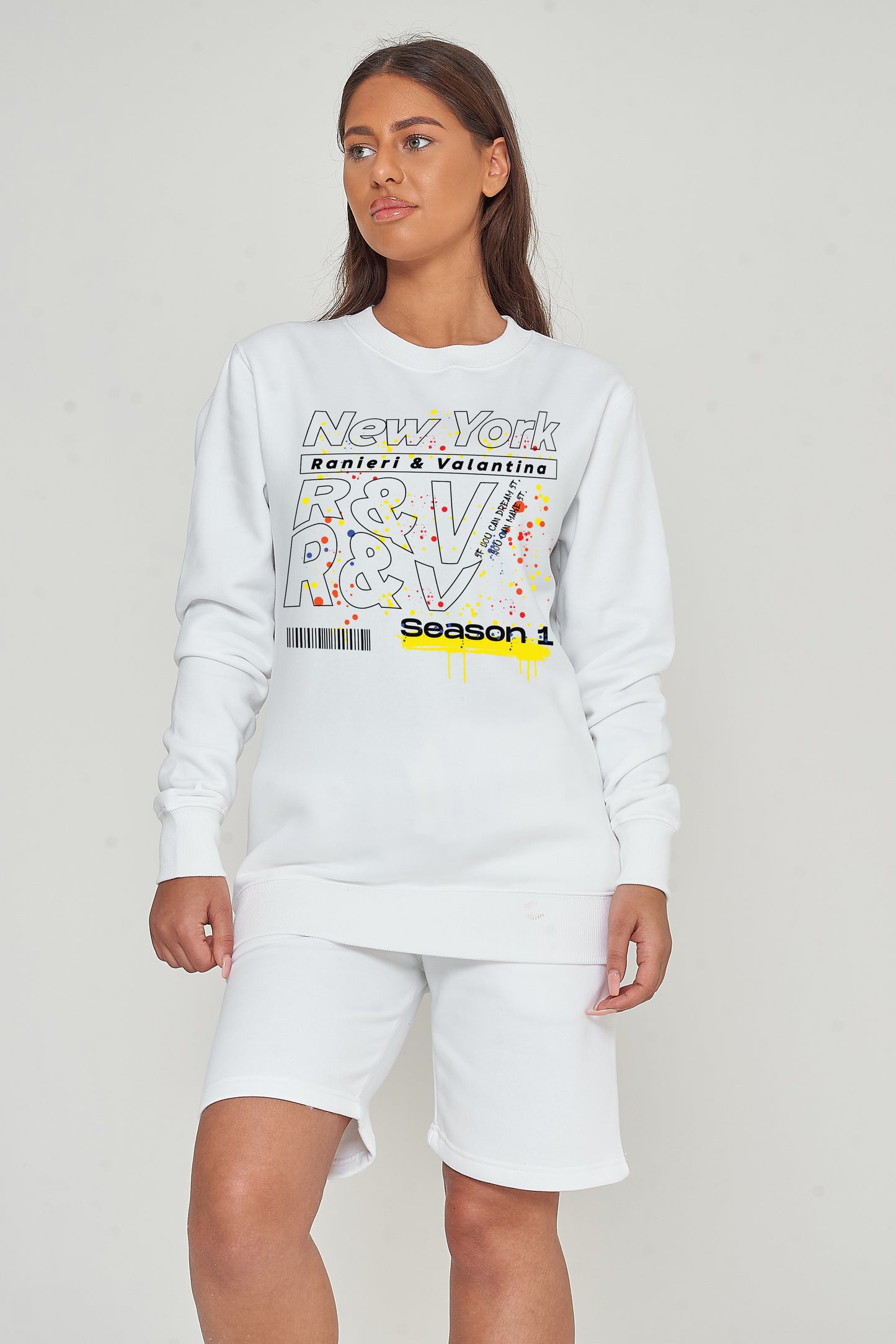 Woman wearing the white New York Season 1 Sweatshirt styled with casual bottoms, highlighting the prominent front graphic print and comfortable fit.