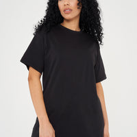 A woman standing in an oversized black t-shirt, displaying a side profile and length.