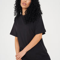 Woman wearing oversized black t-shirt and casual shorts, front view highlighting loose silhouette. 