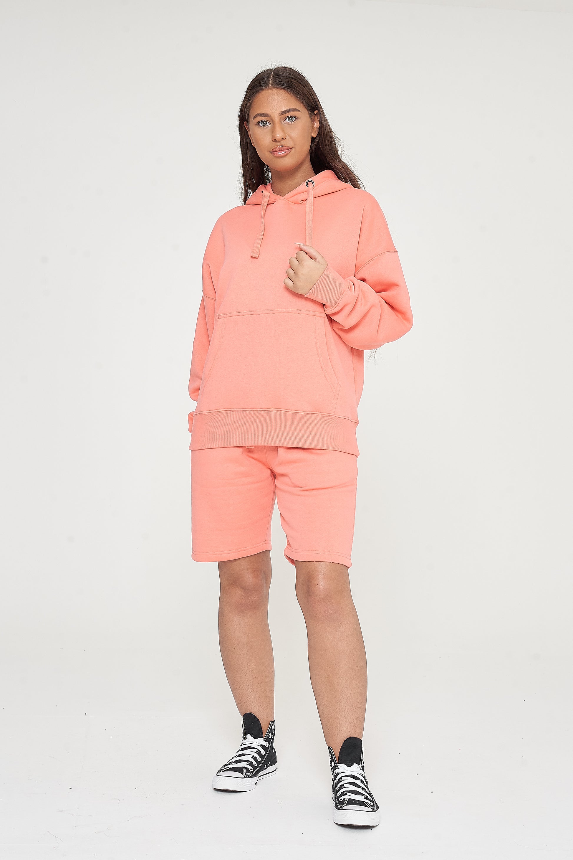 Woman wearing oversized coral hoodie and matching shorts, front-facing pose. 