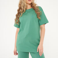 Woman standing in oversized green t-shirt and shorts, casual pose highlighting color and comfort. 