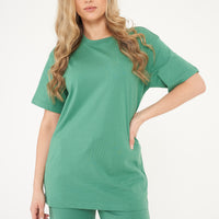 Woman showcasing oversized green t-shirt and shorts from a side angle, displaying relaxed fit. 