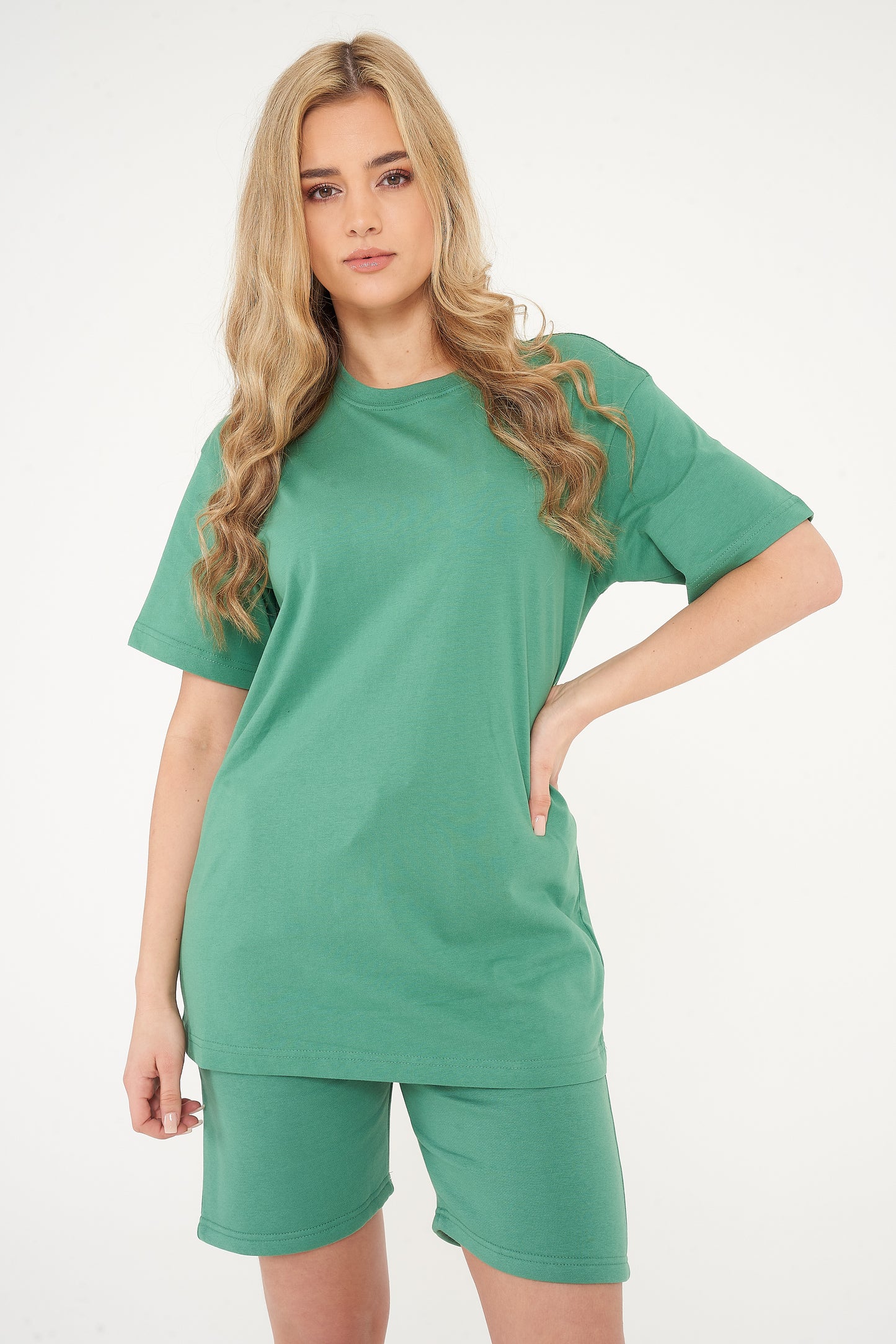 Woman showcasing oversized green t-shirt and shorts from a side angle, displaying relaxed fit. 