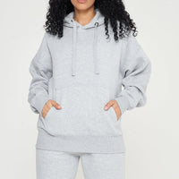 Woman standing in a grey oversized hoodie and shorts, casual pose for versatile styling.
