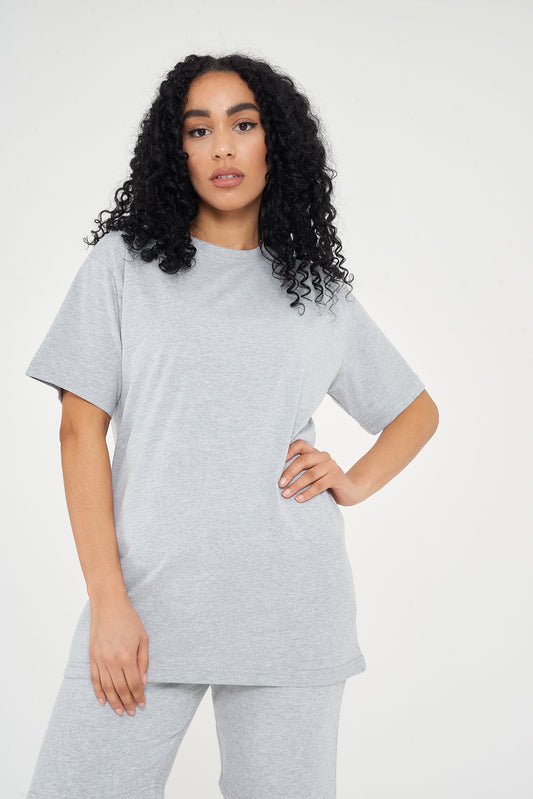 Woman modeling oversized grey t-shirt in a standing side pose, showing relaxed silhouette. 
