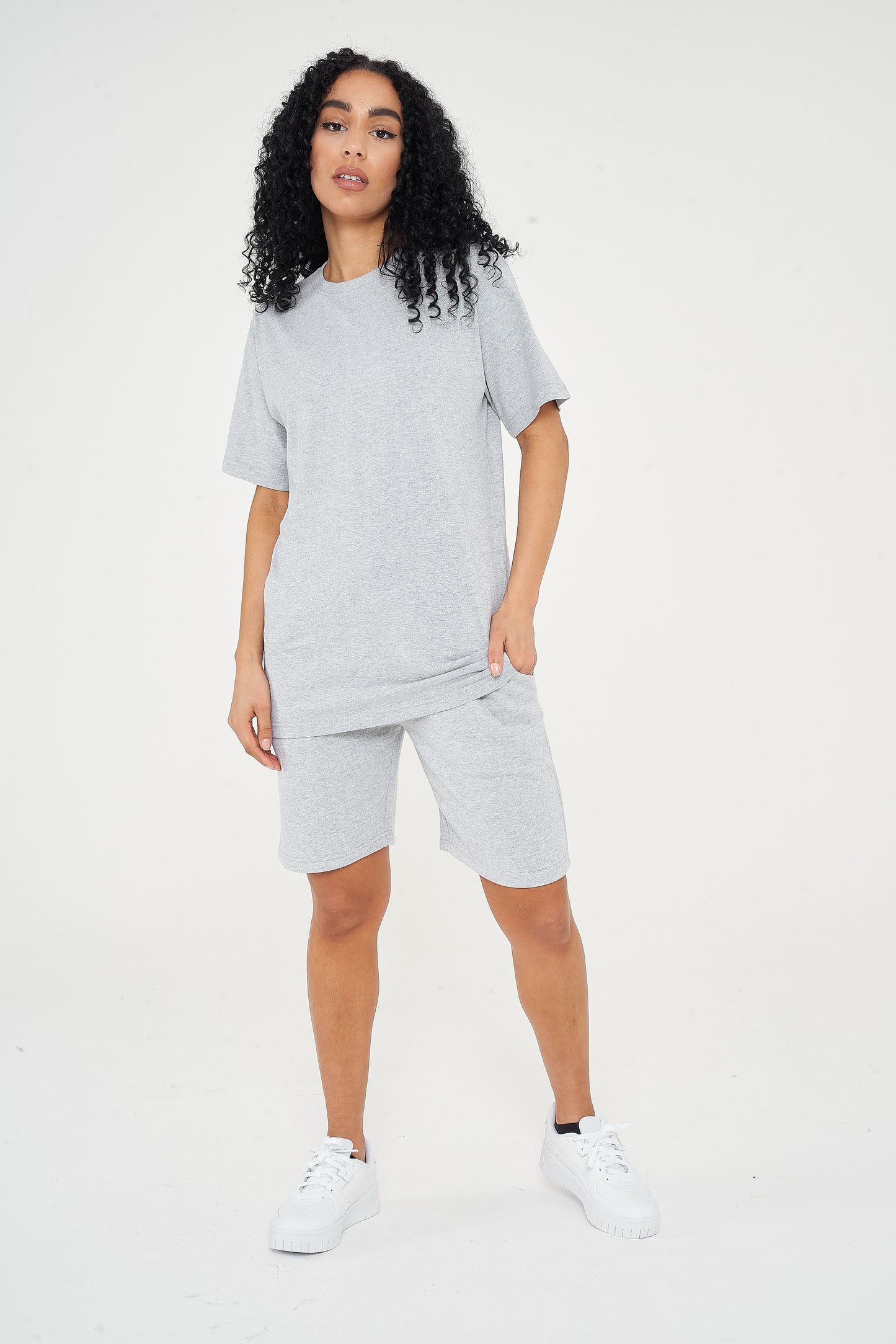 A woman wearing an oversized grey t-shirt with casual shorts, front-facing. 