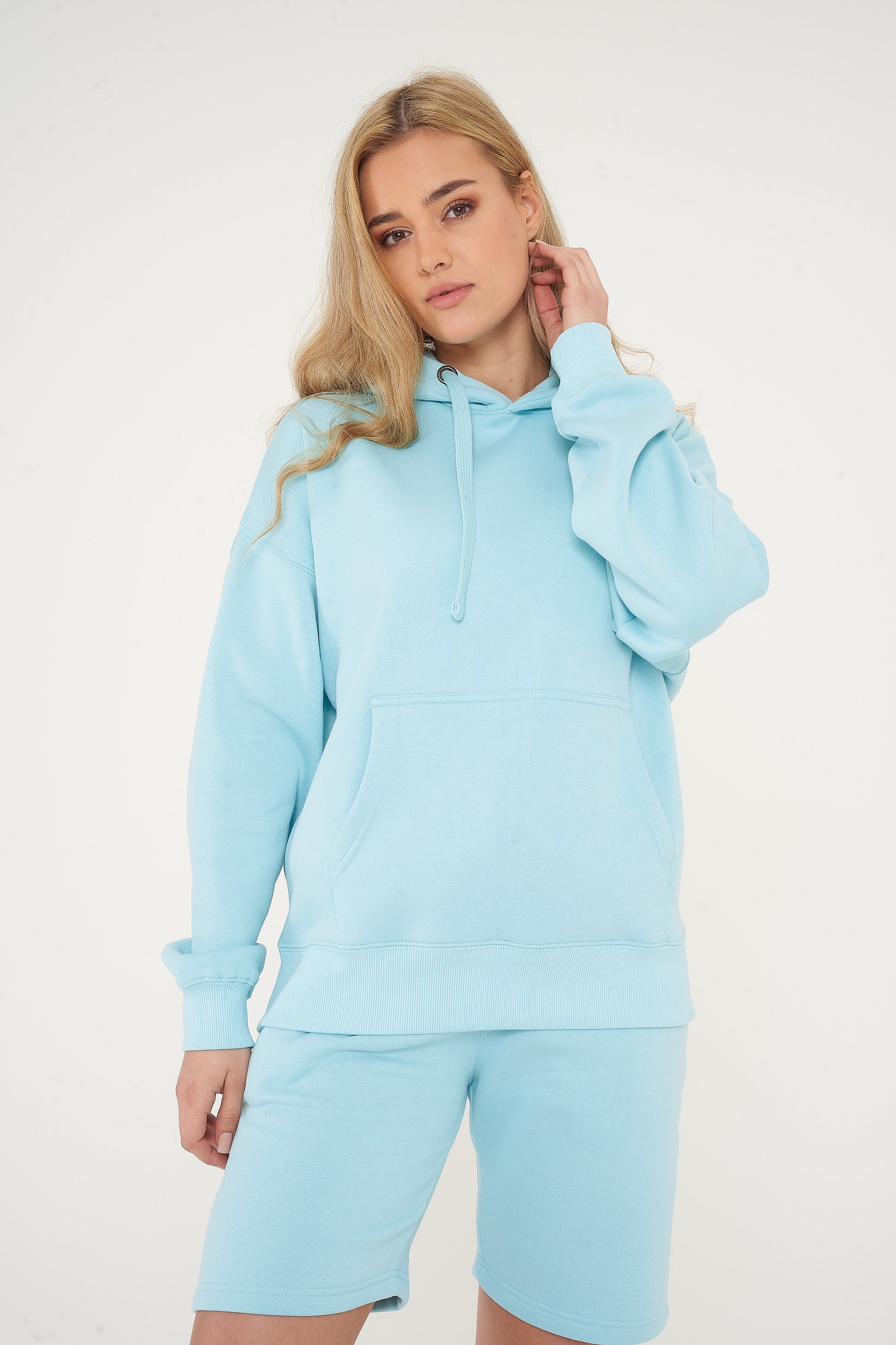 Woman modeling turquoise oversized hoodie in a sideways pose, showing roomy fit. 