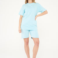 Woman modeling a turquoise oversized t-shirt from the side, highlighting the roomy fit.