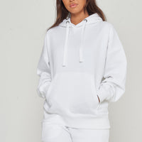 Woman modeling oversized white hoodie in a casual standing pose, side view.