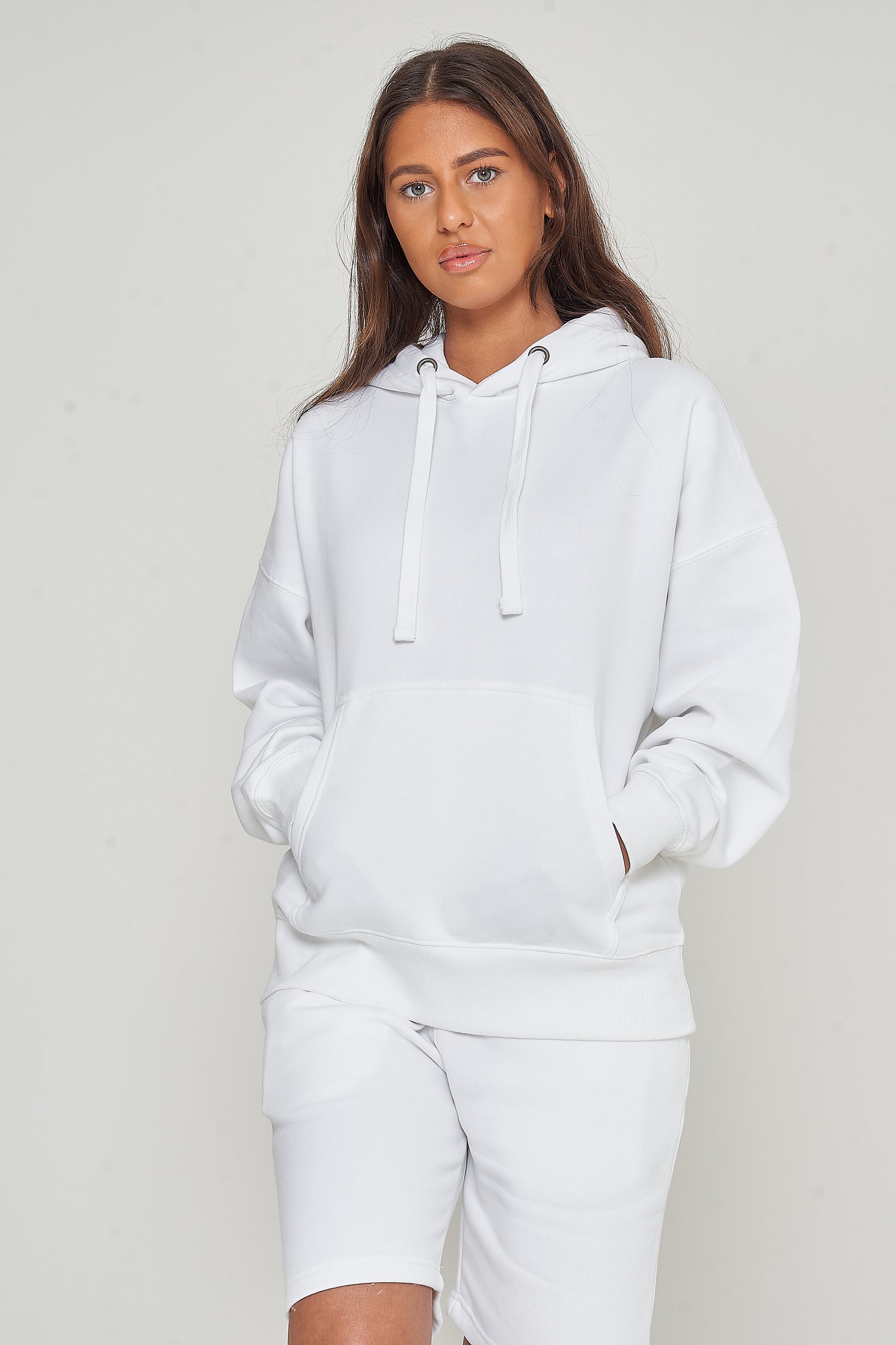 Woman modeling oversized white hoodie in a casual standing pose, side view.