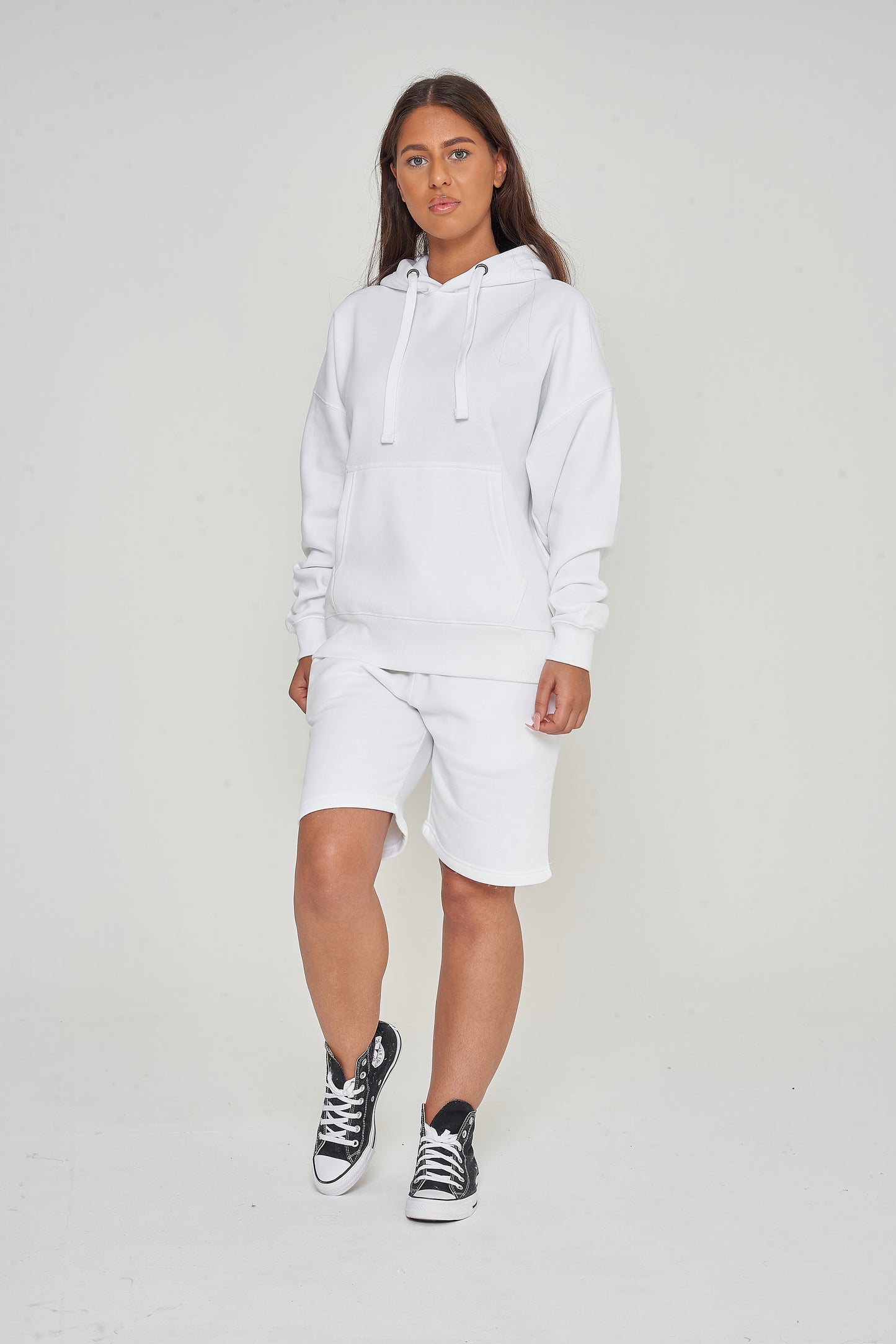 Woman wearing oversized white hoodie with casual shorts, standing front-facing. 