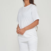 Woman wearing oversized white t-shirt standing sideways, relaxed fit visible. 