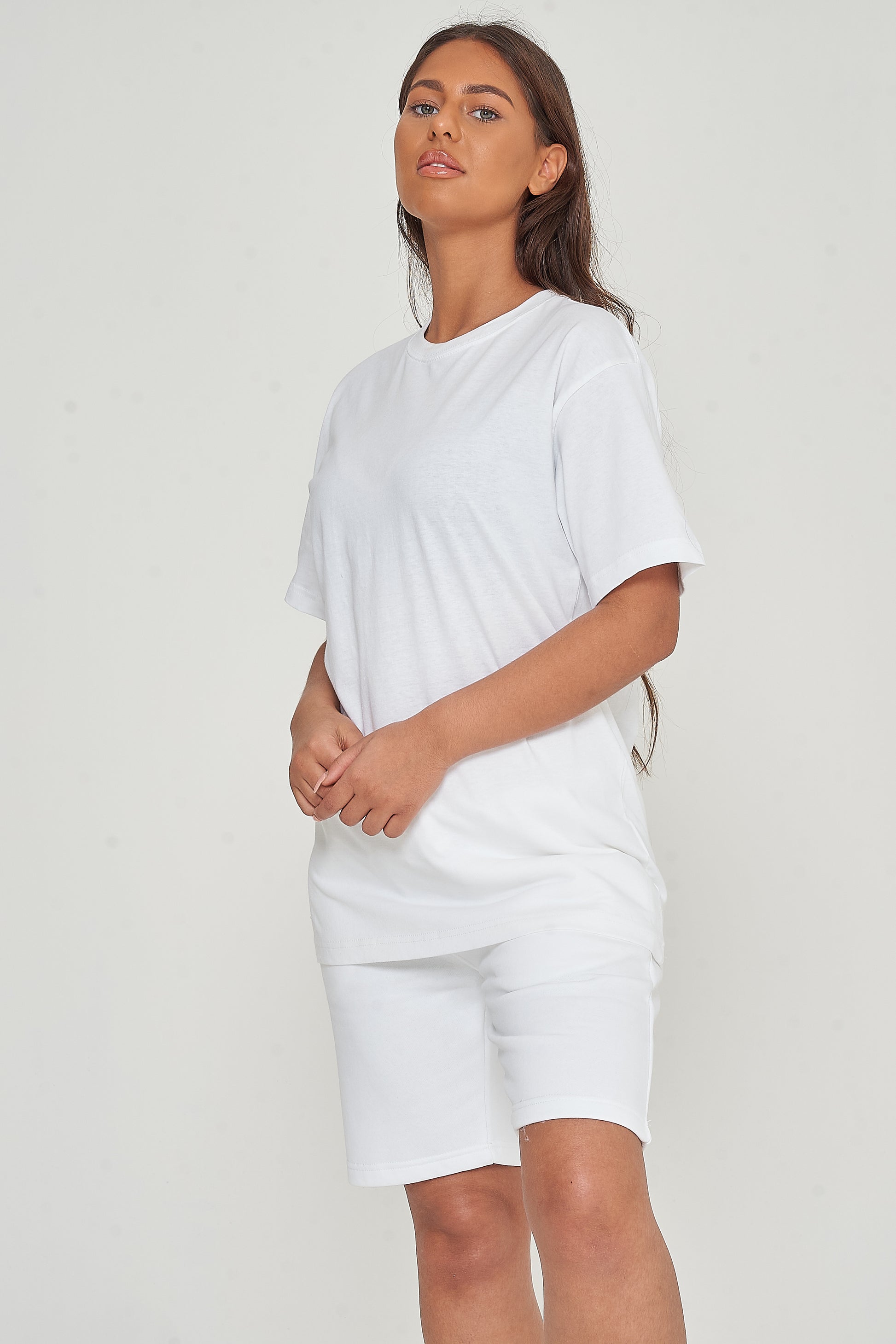 Woman wearing oversized white t-shirt standing sideways, relaxed fit visible. 