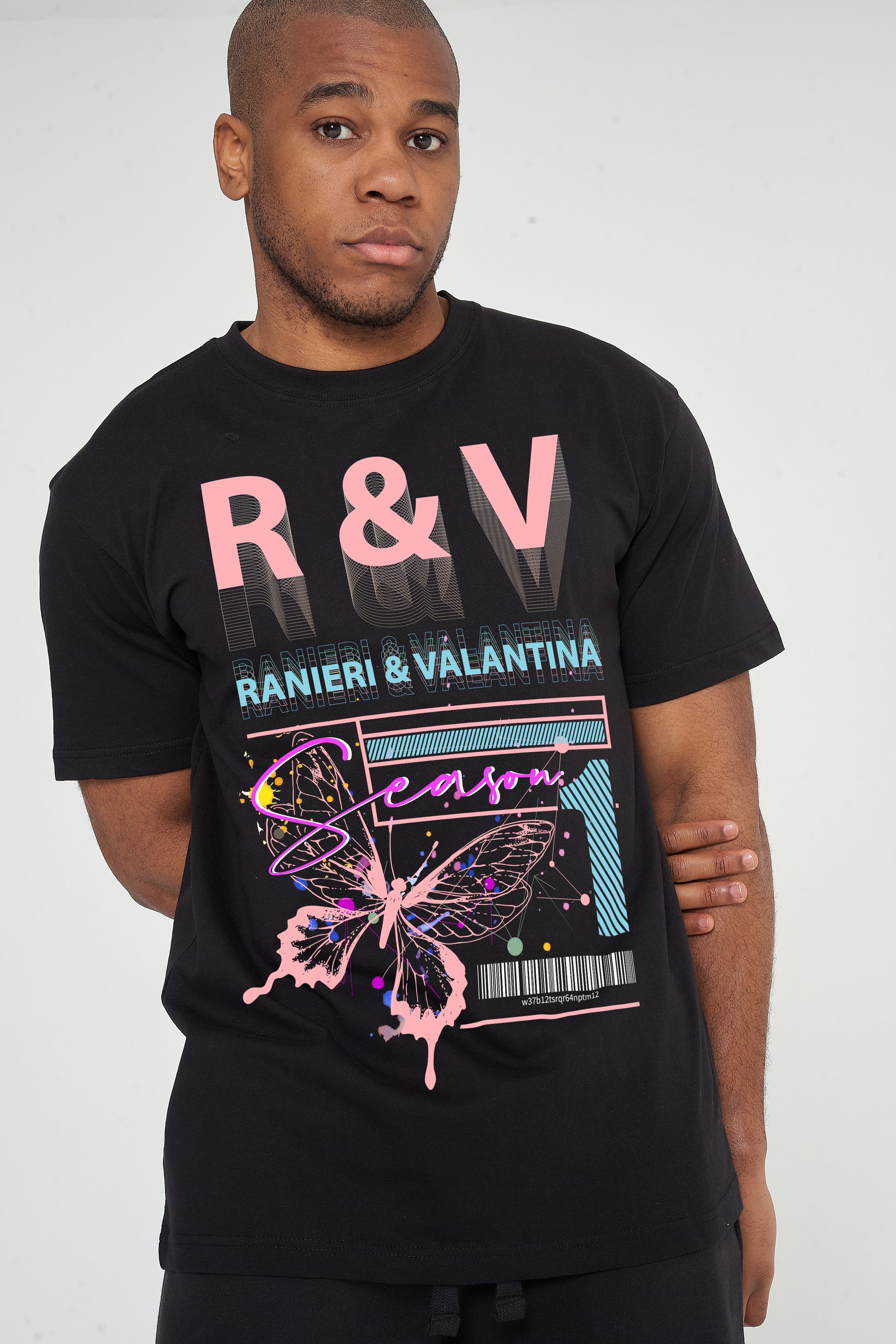 Male model front view wearing black Coral Butterfly Oversized T-shirt with coral butterfly and R&V graphic, styled with casual shorts – oversized fit.