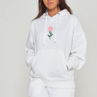 Woman wearing the white Plain Rose Oversized Hoodie styled with casual bottoms, highlighting the minimal rose print and comfortable oversized fit.