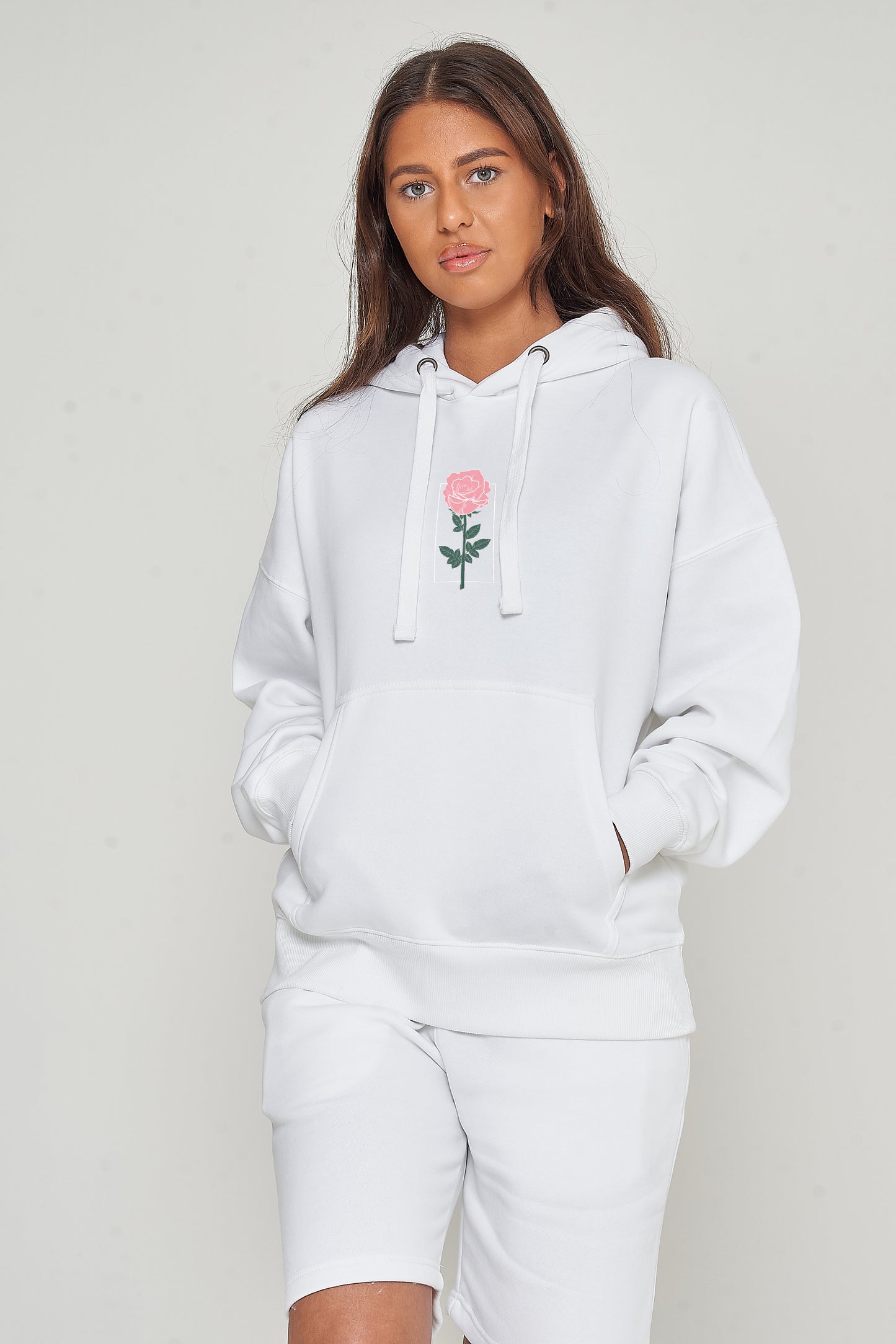 Woman wearing the white Plain Rose Oversized Hoodie styled with casual bottoms, highlighting the minimal rose print and comfortable oversized fit.