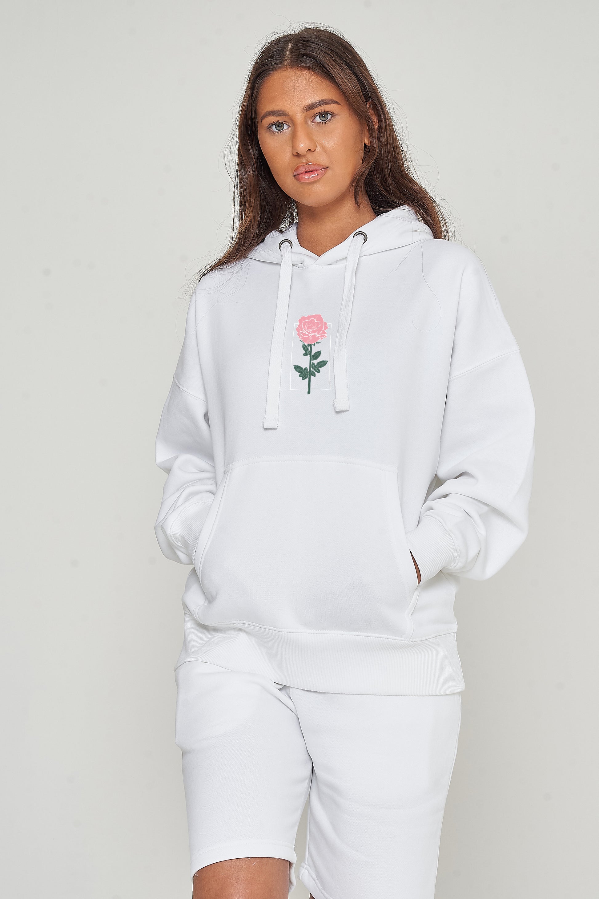 Woman wearing the white Plain Rose Oversized Hoodie styled with casual bottoms, highlighting the minimal rose print and comfortable oversized fit.