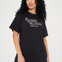 Woman wearing black oversized Signature Beverly Hills T-shirt, styled with casual shorts, showing front logo print.