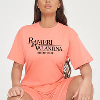 Woman wearing coral oversized Signature Beverly Hills T-shirt and matching shorts, highlighting front logo and streetwear style.