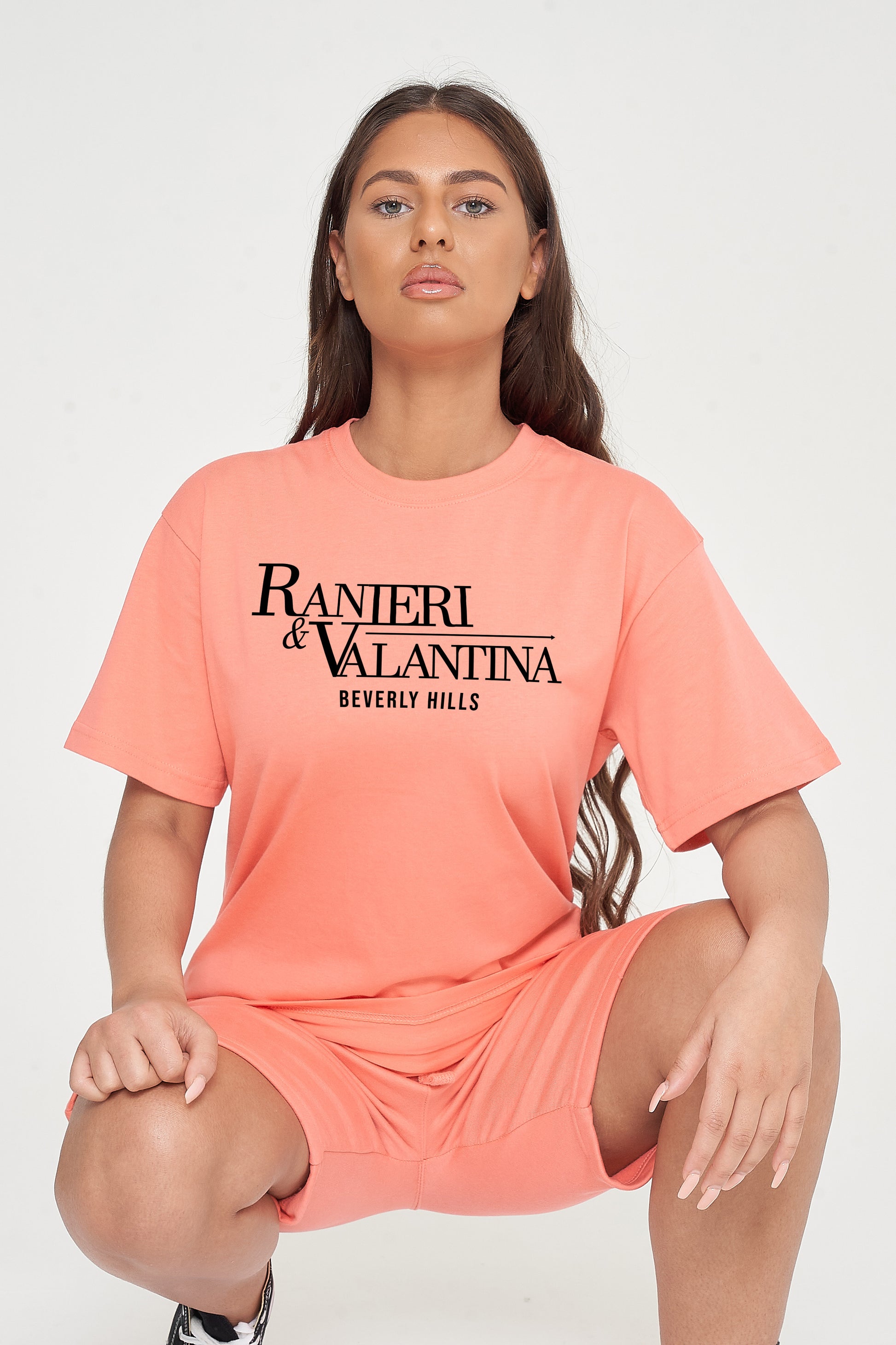 Woman wearing coral oversized Signature Beverly Hills T-shirt and matching shorts, highlighting front logo and streetwear style.