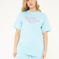 Woman wearing turquoise oversized Signature Beverly Hills T-shirt and shorts, highlighting front logo print.