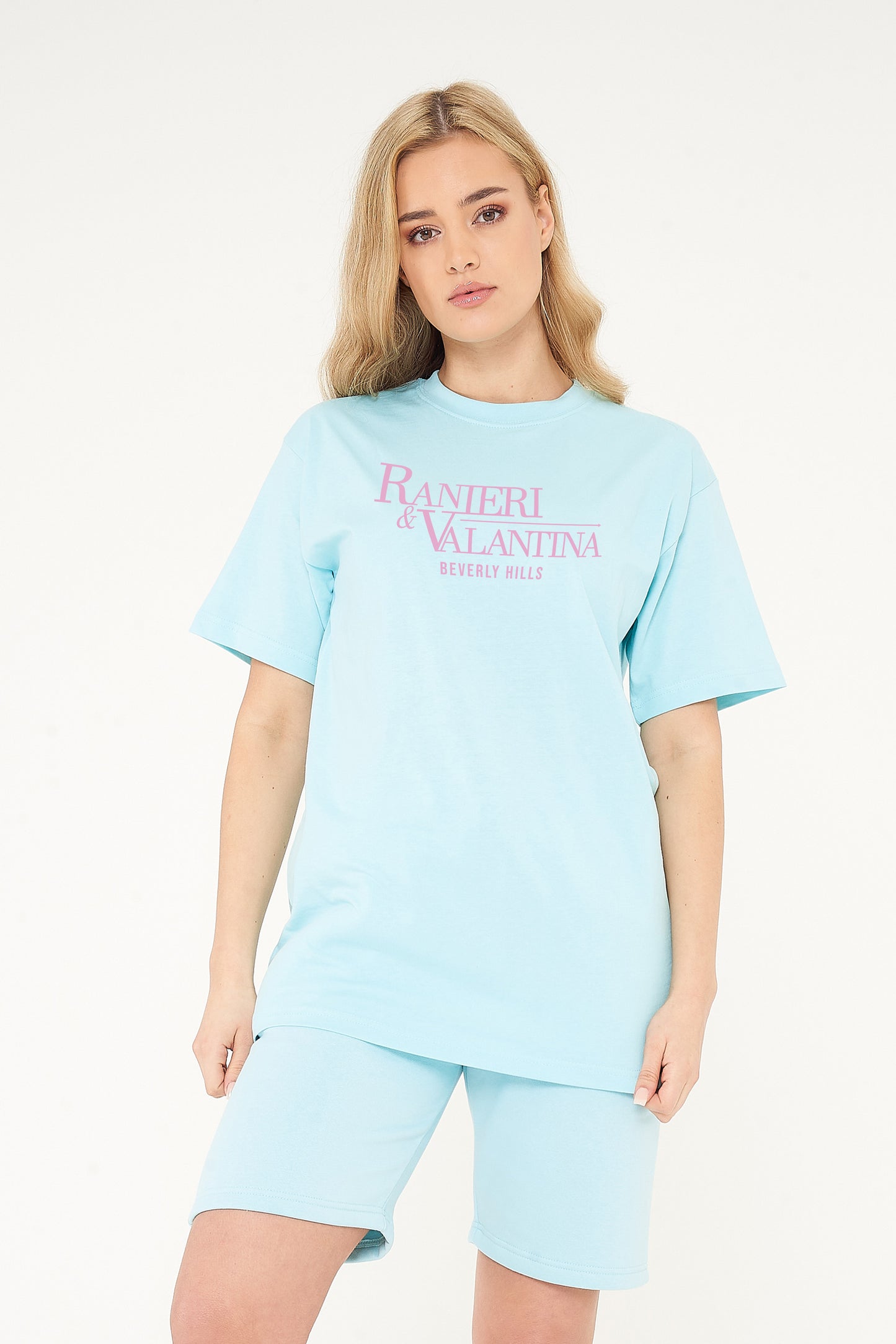 Woman wearing turquoise oversized Signature Beverly Hills T-shirt and shorts, highlighting front logo print.