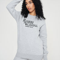 Woman wearing a grey Signature Beverly Hills sweatshirt styled with shorts for a modern UK streetwear look.