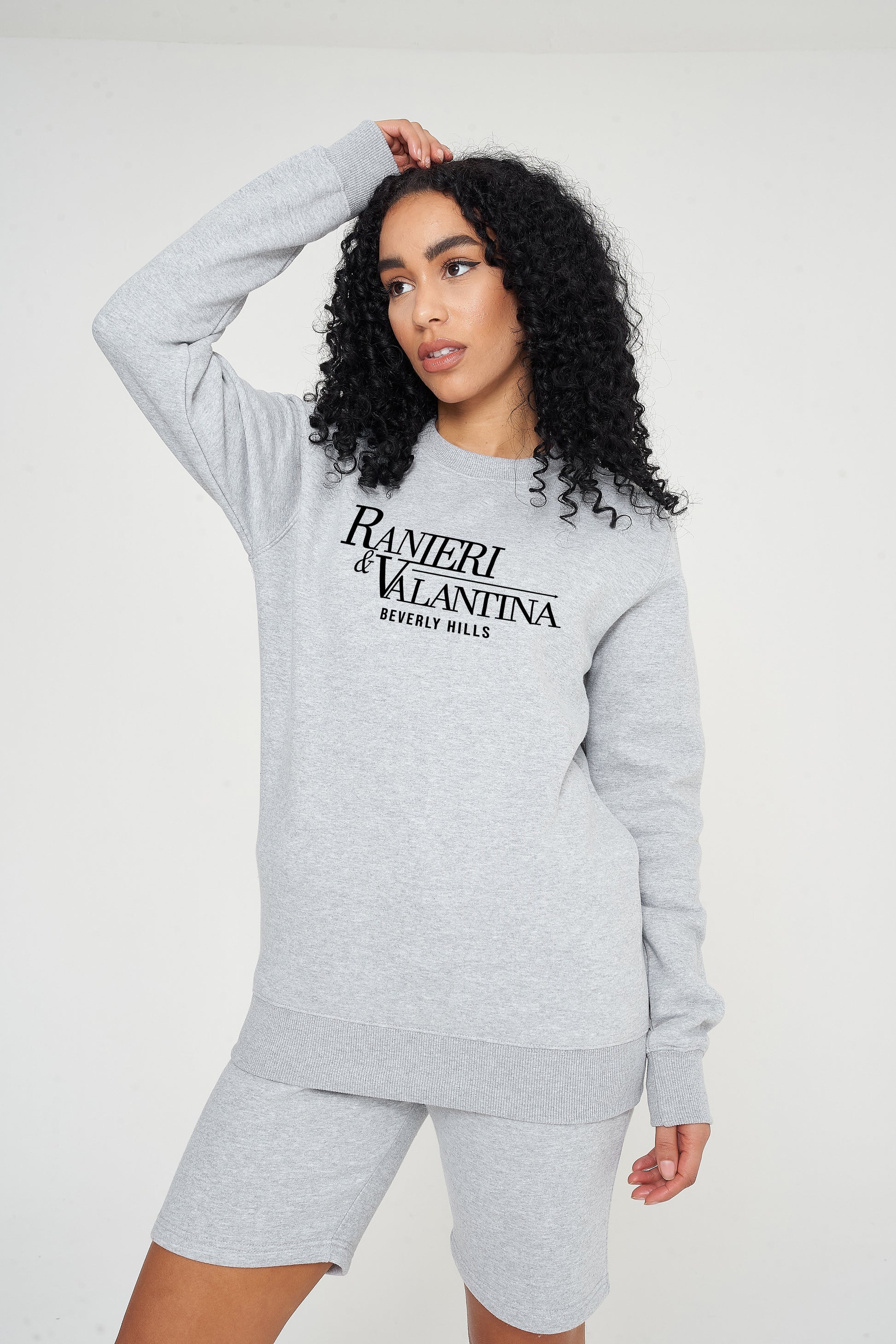 Woman wearing a grey Signature Beverly Hills sweatshirt styled with shorts for a modern UK streetwear look.