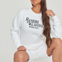 Woman wearing white Signature Beverly Hills sweatshirt paired with shorts, styled for a modern UK streetwear look.