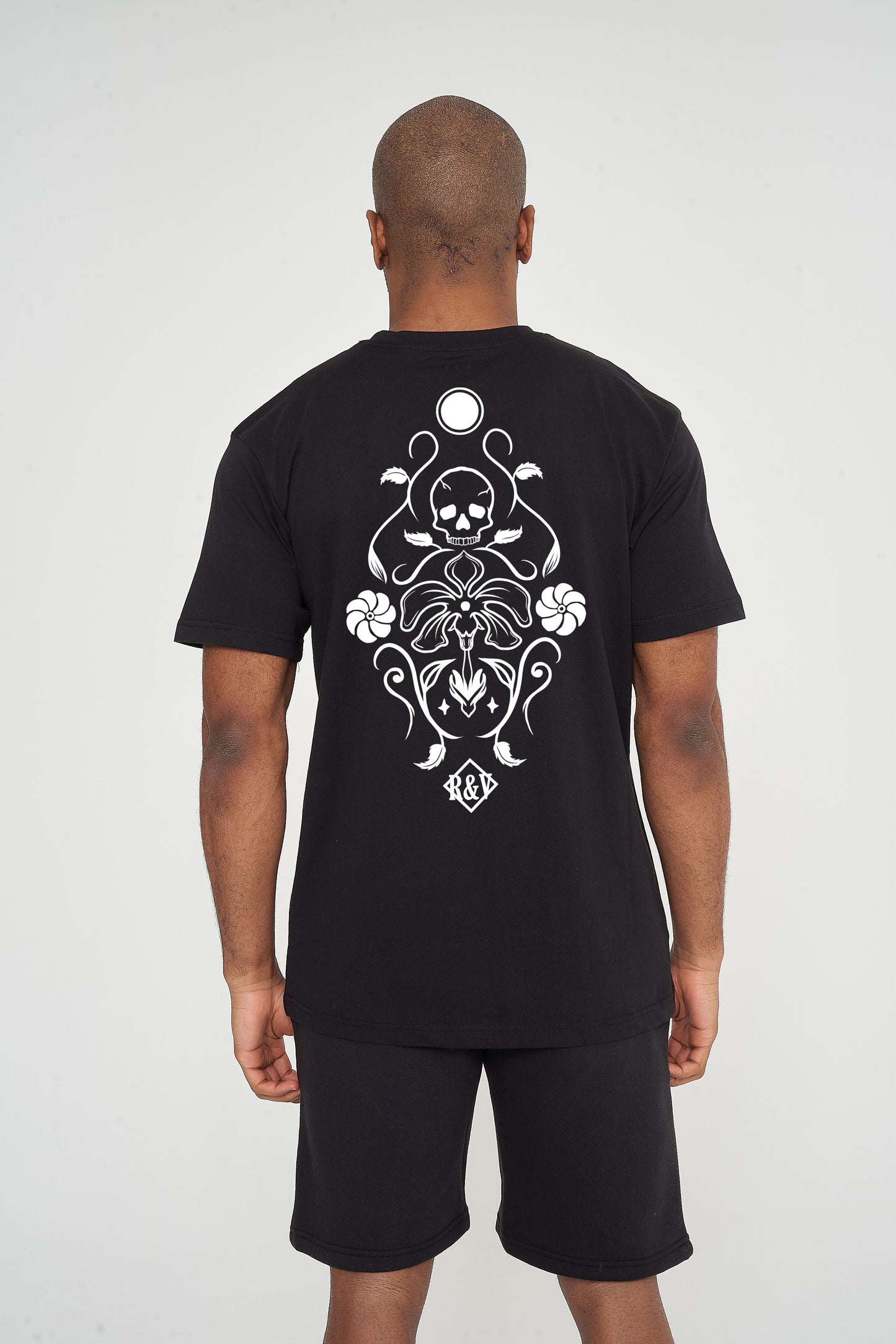 Man wearing the black Skull Tattoo Oversized T-Shirt styled with casual bottoms, showcasing the striking back graphic and comfortable fit.