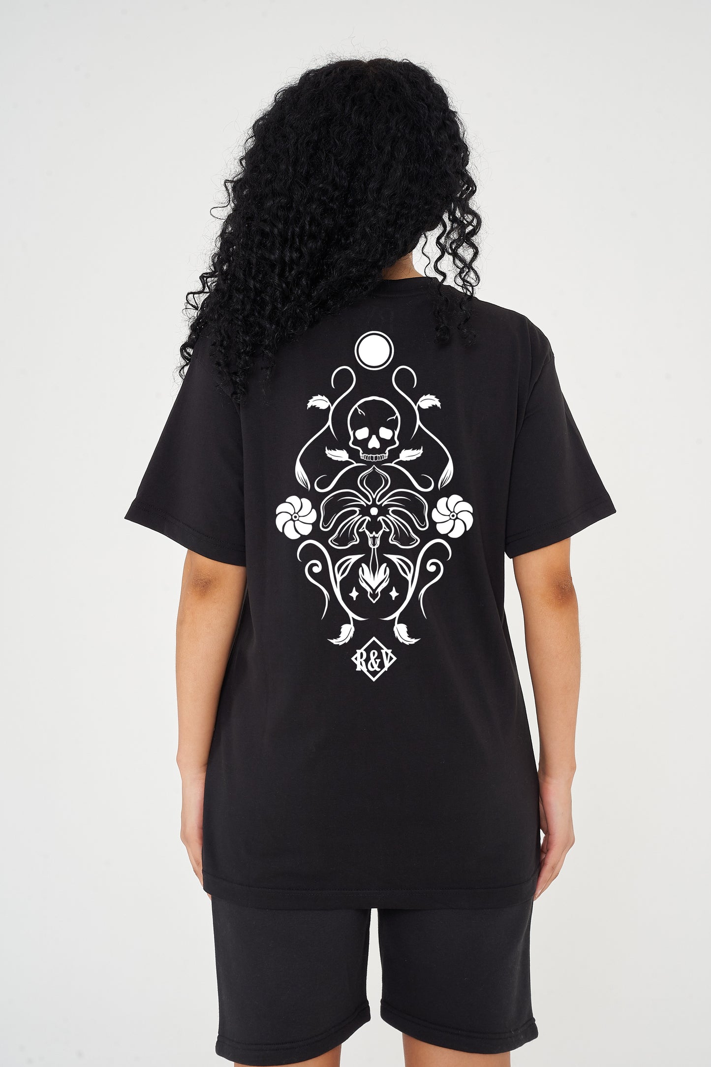 Woman wearing the black Skull Tattoo Oversized T-Shirt styled with casual bottoms, showcasing the striking back graphic and comfortable fit.