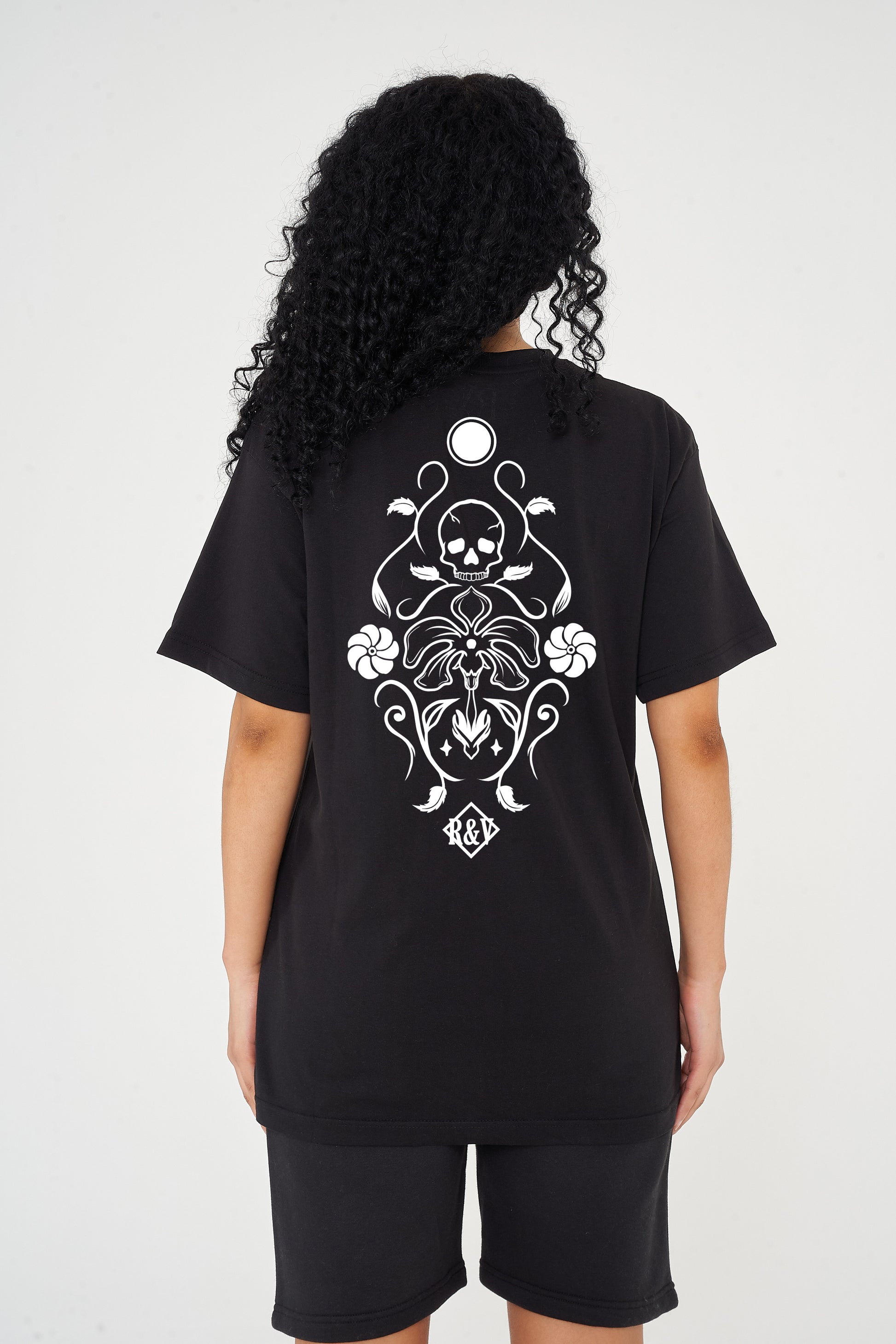 Woman wearing the black Skull Tattoo Oversized T-Shirt styled with casual bottoms, showcasing the striking back graphic and comfortable fit.
