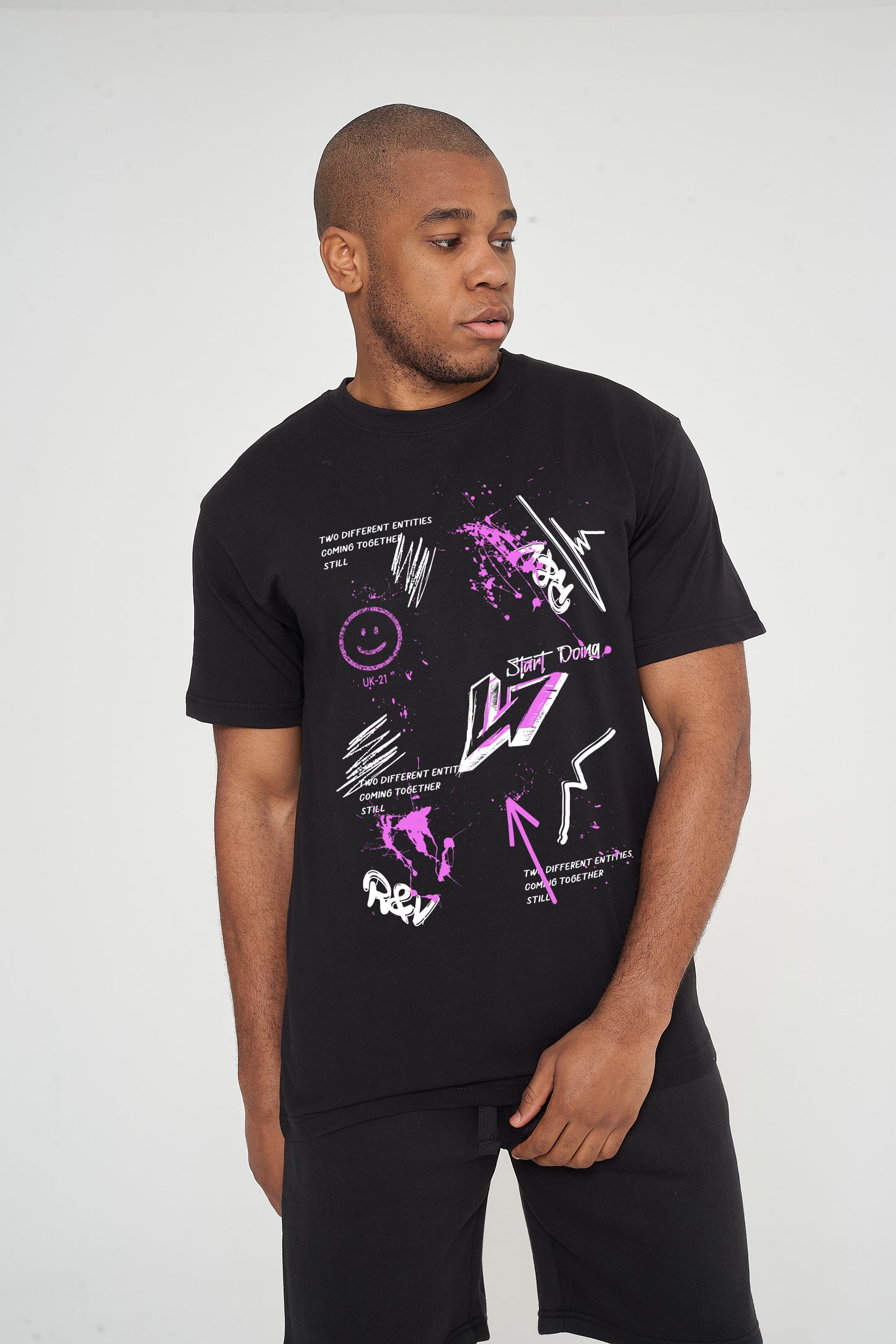 Male model front view wearing black oversized T-shirt with graffiti print, arms down, modern streetwear look.