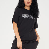 Woman wearing the black Strong Woman Oversized T-Shirt styled with casual bottoms, highlighting the empowering front print and comfortable silhouette.