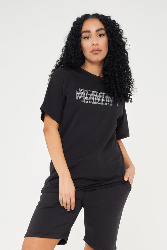 Woman wearing the black Strong Woman Oversized T-Shirt styled with casual bottoms, highlighting the empowering front print and comfortable silhouette.